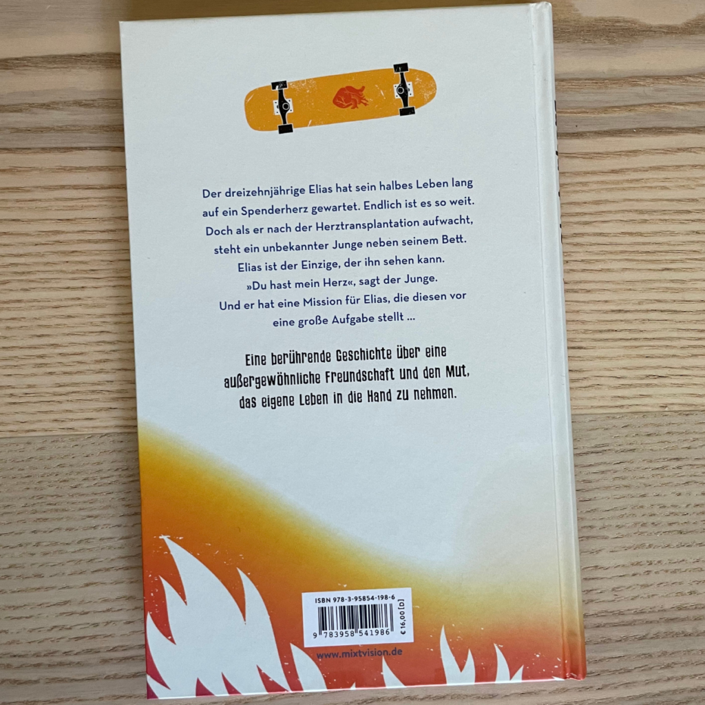 Das Buch "Skaterherz" liegt mit der Buchrückseite nach oben auf einem Holztisch.