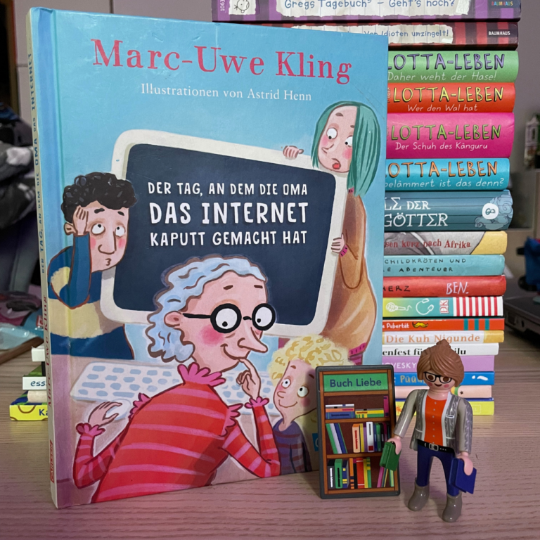 Zu sehen ist das Buch "Der Tag, an dem die Oma das INternet kaputt gemacht hat". Das Buch steht vor einem Stapel andere Kinderbücher. Neben dem Buch steht die Playmobilfigur die Buchhändlerin.